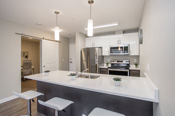 A modern kitchen with a white countertop and stainless steel appliances.